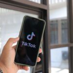 Close-up of a hand holding a smartphone displaying the TikTok app indoors.